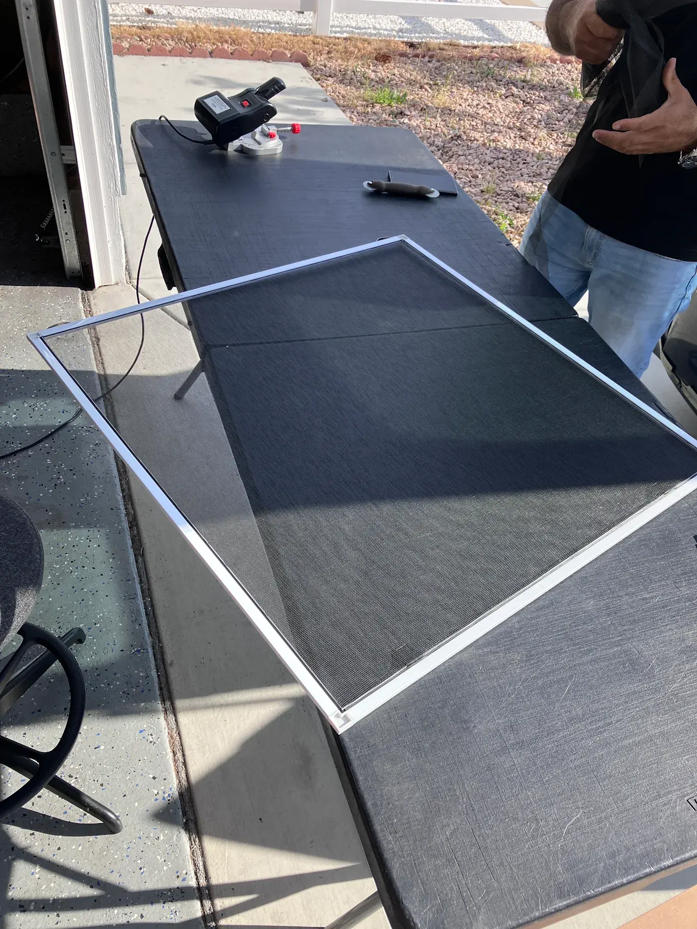 Technician assembling a window screen on an outdoor work table